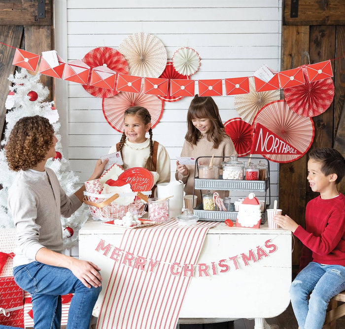Red envelope advent banner at a Christmas hot cocoa party with kids and a Merry Christmas banner