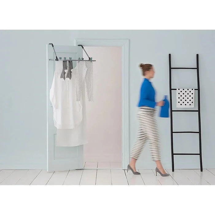 Lifestyle view of the Brabantia over the door drying rack hung over a door and lady walking who is blurred.