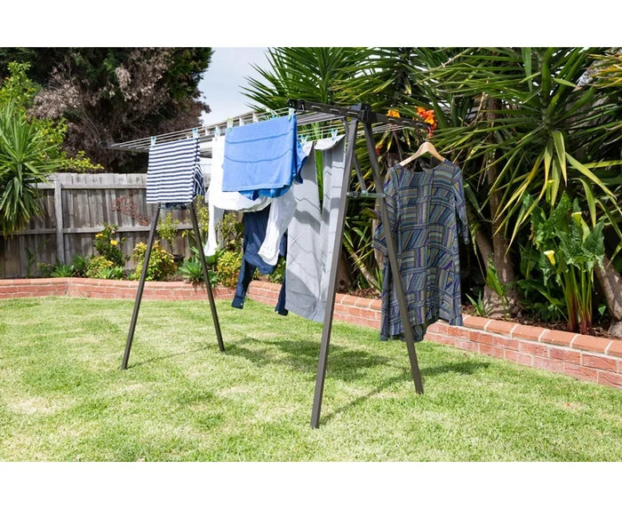 Daytek portable clothesline in use in an outdoor backyard setting with laundry drying on a sunny day.