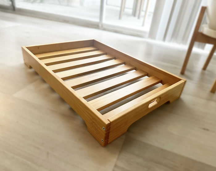 Empty wooden Bark Potty tray sleeve viewed at an angle on a hardwood floor.
