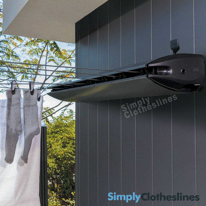 Hills Retractable 7 Line clothesline installed on a dark outdoor wall with garments hanging to dry.