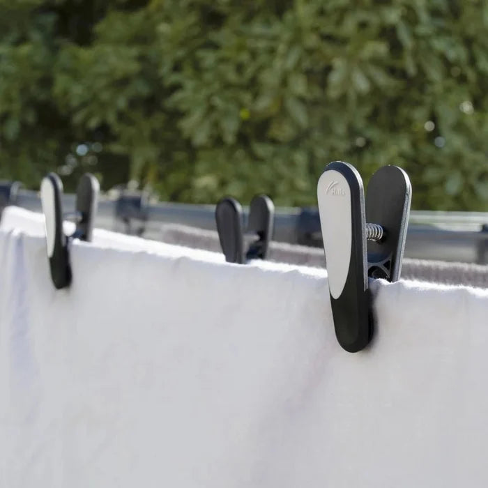 Close-up of Hills Soft Grip pegs in use on a clothesline, showing the ergonomic grip and secure hold on a white garment.