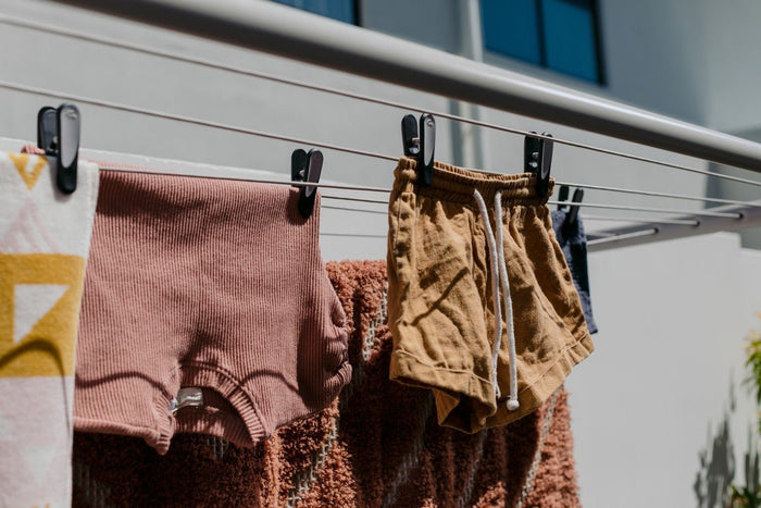 Row of Hills Soft Grip pegs securing various garments to an outdoor fold down clothesline.